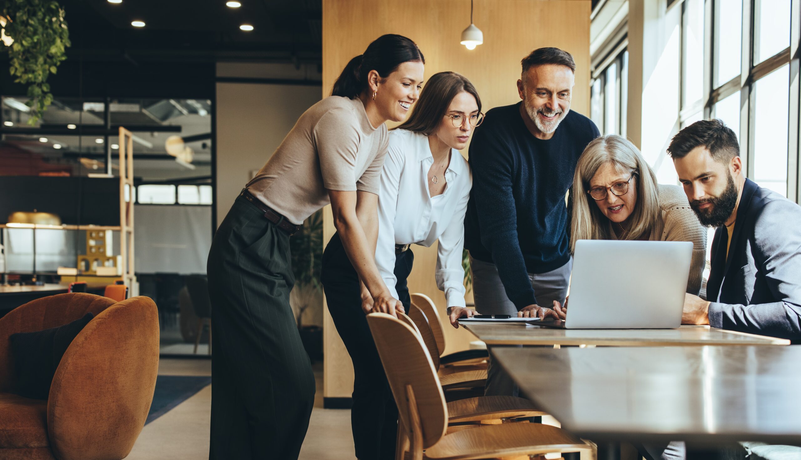group,of,diverse,businesspeople,using,a,laptop,while,collaborating,on