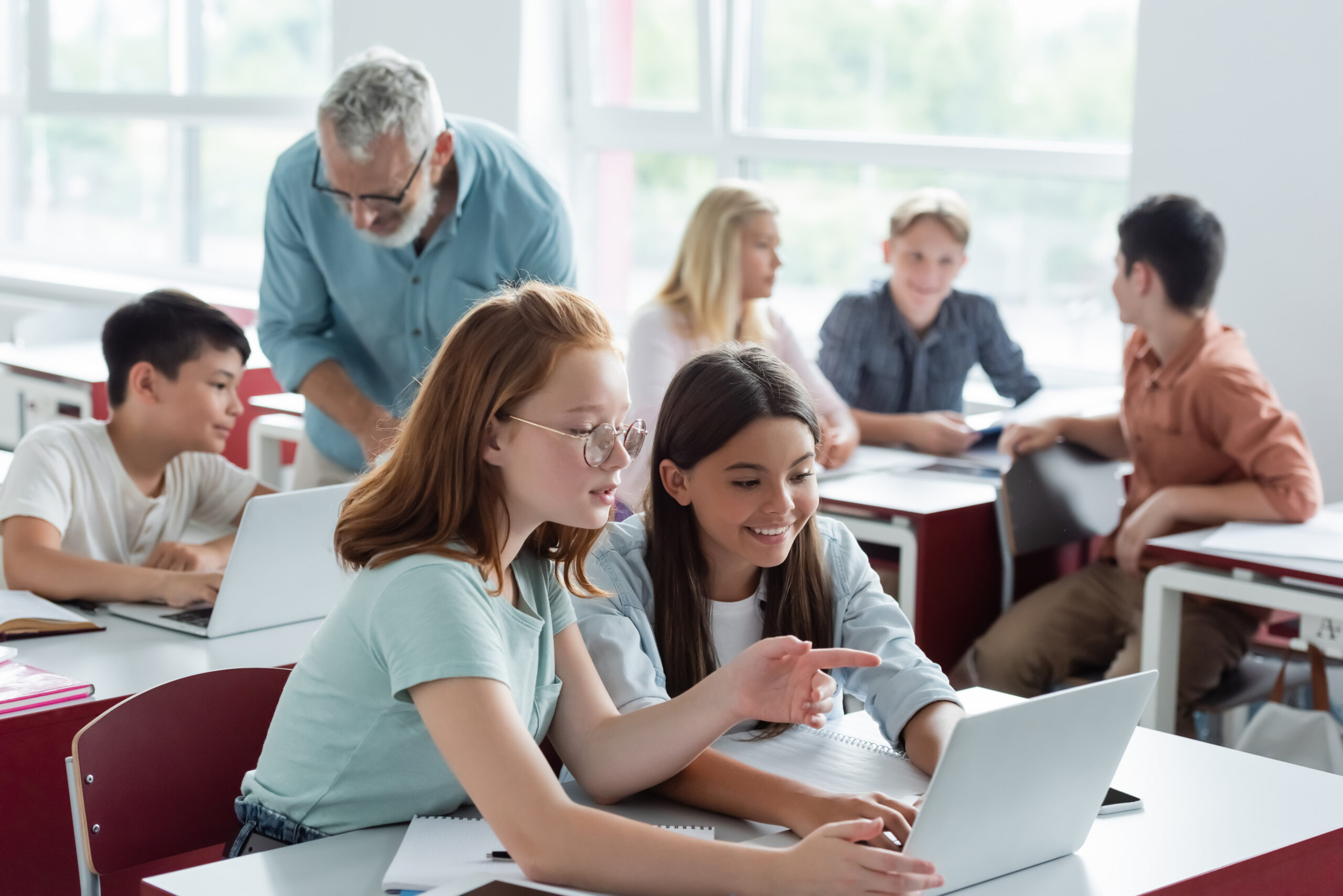 schoolkid,pointing,at,laptop,near,teacher,and,multiethnic,classmates